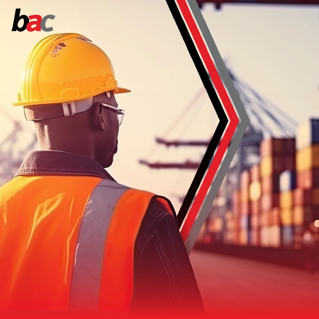 Logistics worker with hard hat using a tablet in a shipping container yard (BAC).