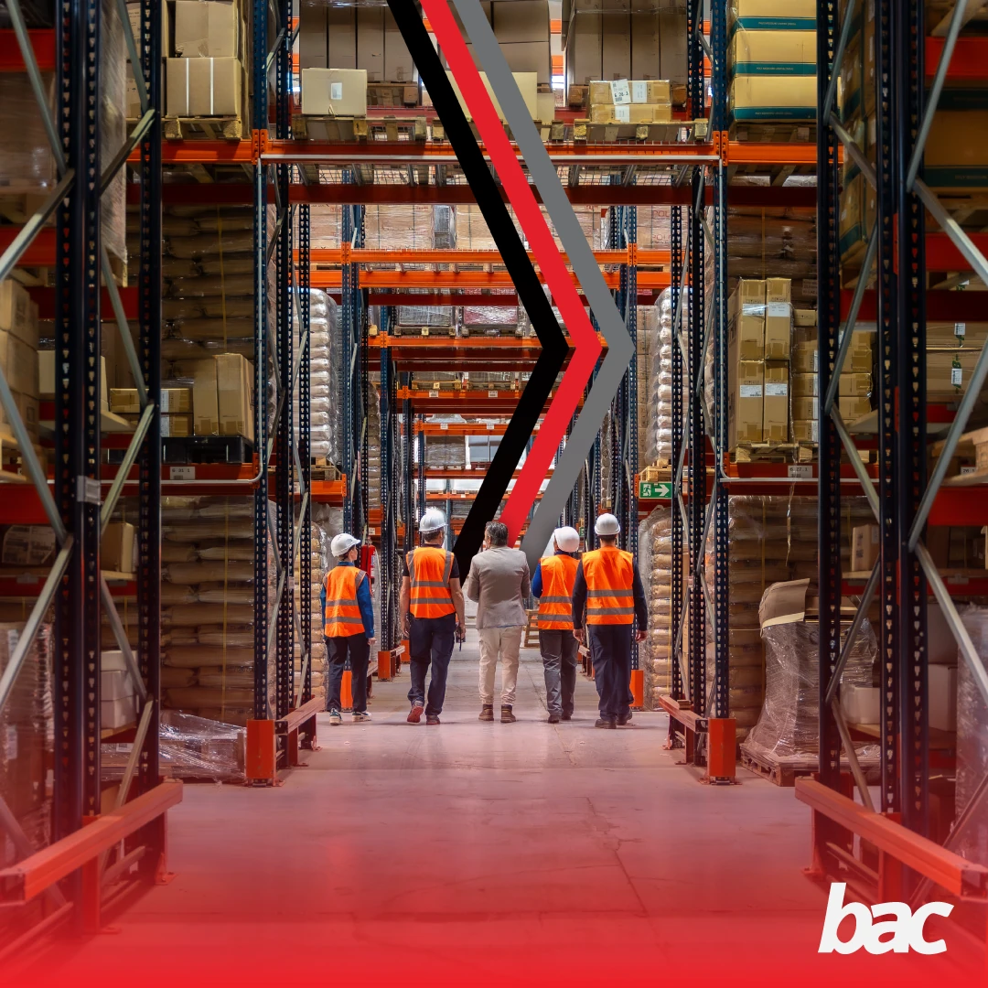 Warehouse aisle with safety-vest team inspecting stored cargo, BAC branding