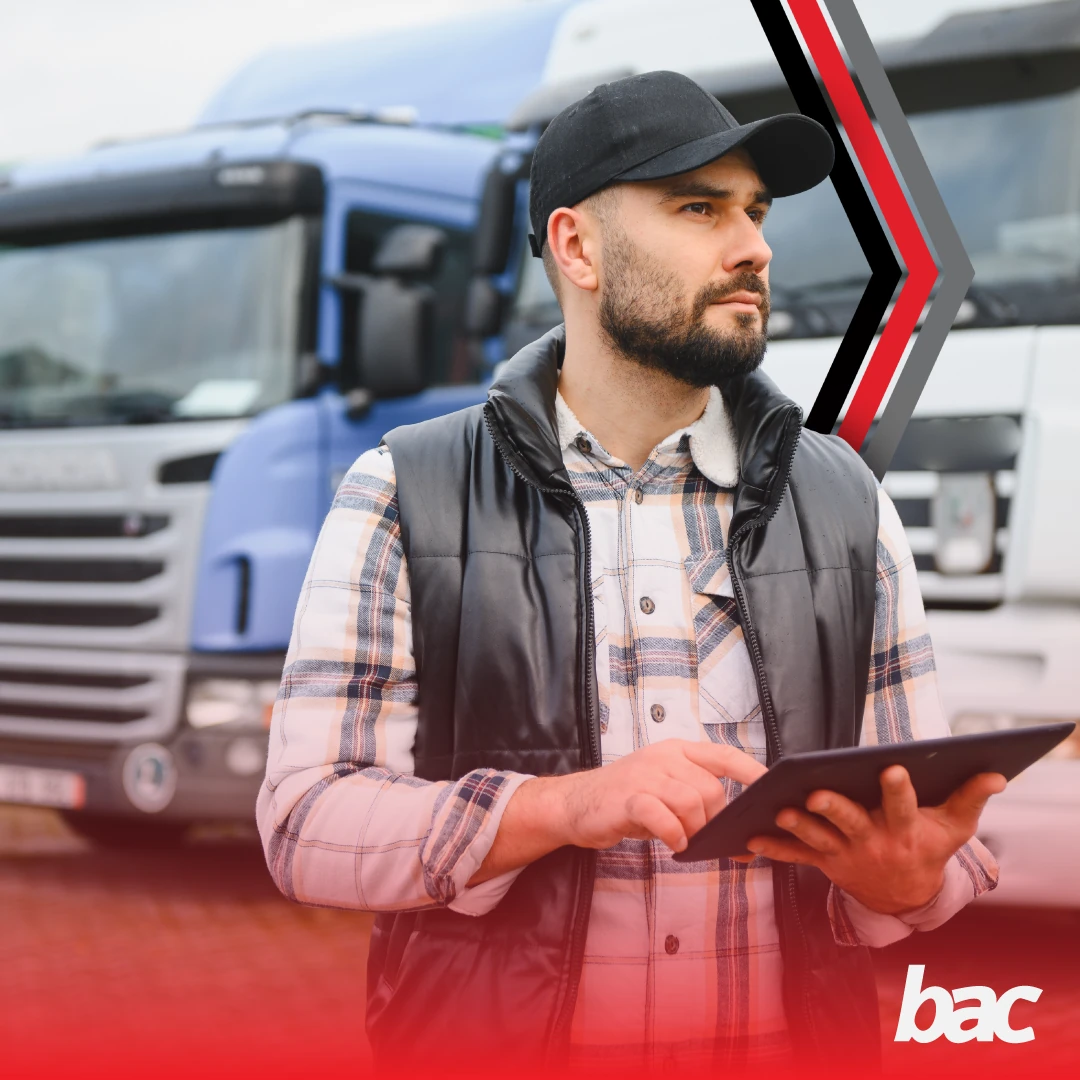 Logistics professional using a tablet in front of trucks for road freight planning